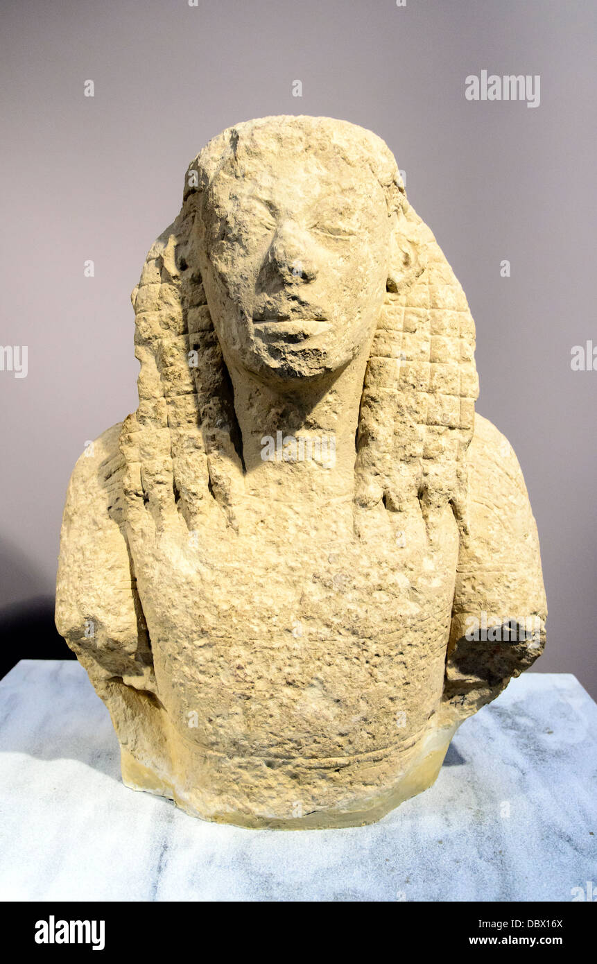 Upper body of a Daedalic statue of a Kore made of poros stone. She wears peplos and epiblema, a kind of cape covering the shoulders. Her triangular face with enhanced features and the particular 'daedalic' coiffure are distinguishing elements of archaic sculpture. Eleftherna, Archaic period, 7th cent. BC Archaeological Museum of Heraklion - Crete, Greece Stock Photo