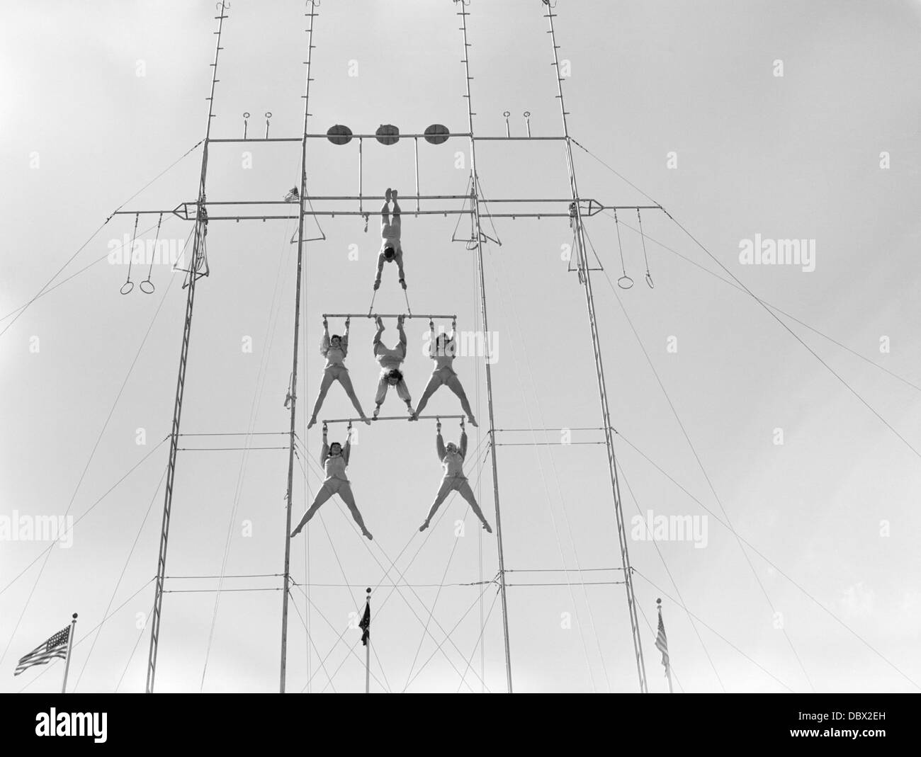 1950s SIX CIRCUS PERFORMERS BALANCED ON HIGH TRAPEZE Stock Photo