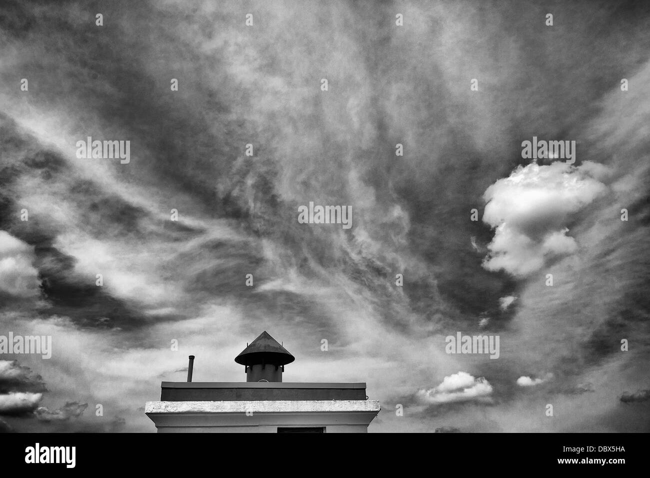 Dramatic clouds and sky over chimney in black and white Stock Photo