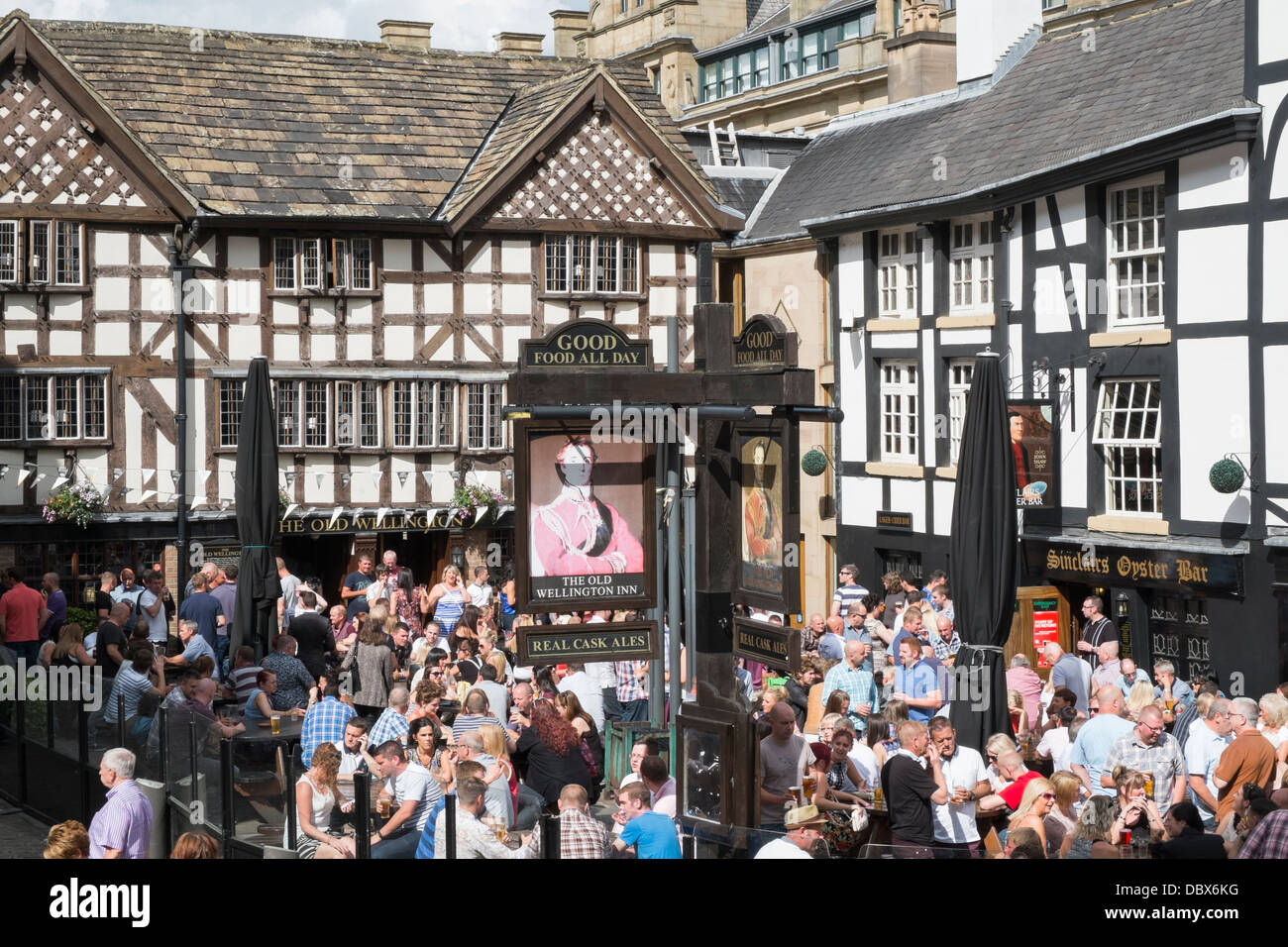 Crowds of people outside 16th century timbered The Old Wellington Inn 1552 in summer in crowded beer garden. Shambles Square Manchester England UK Stock Photo