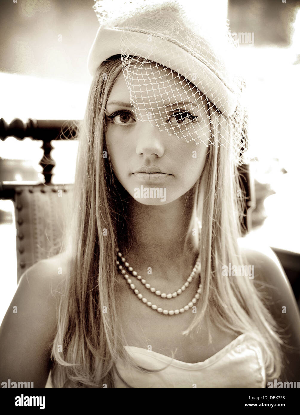 A vintage 1920's inspired photograph of a blonde woman in elegant pearls and a veiled hat Stock Photo