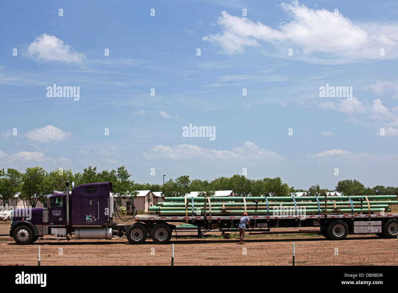 A worker secures a load of pipe on his truck for use in the Eagle Ford Shale, an area of intense oil and gas production. Stock Photo
