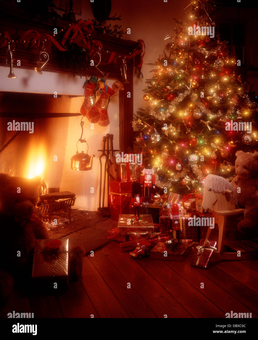 1980s NOSTALGIC CHRISTMAS TREE STANDING BESIDE COLONIAL FIREPLACE Stock Photo