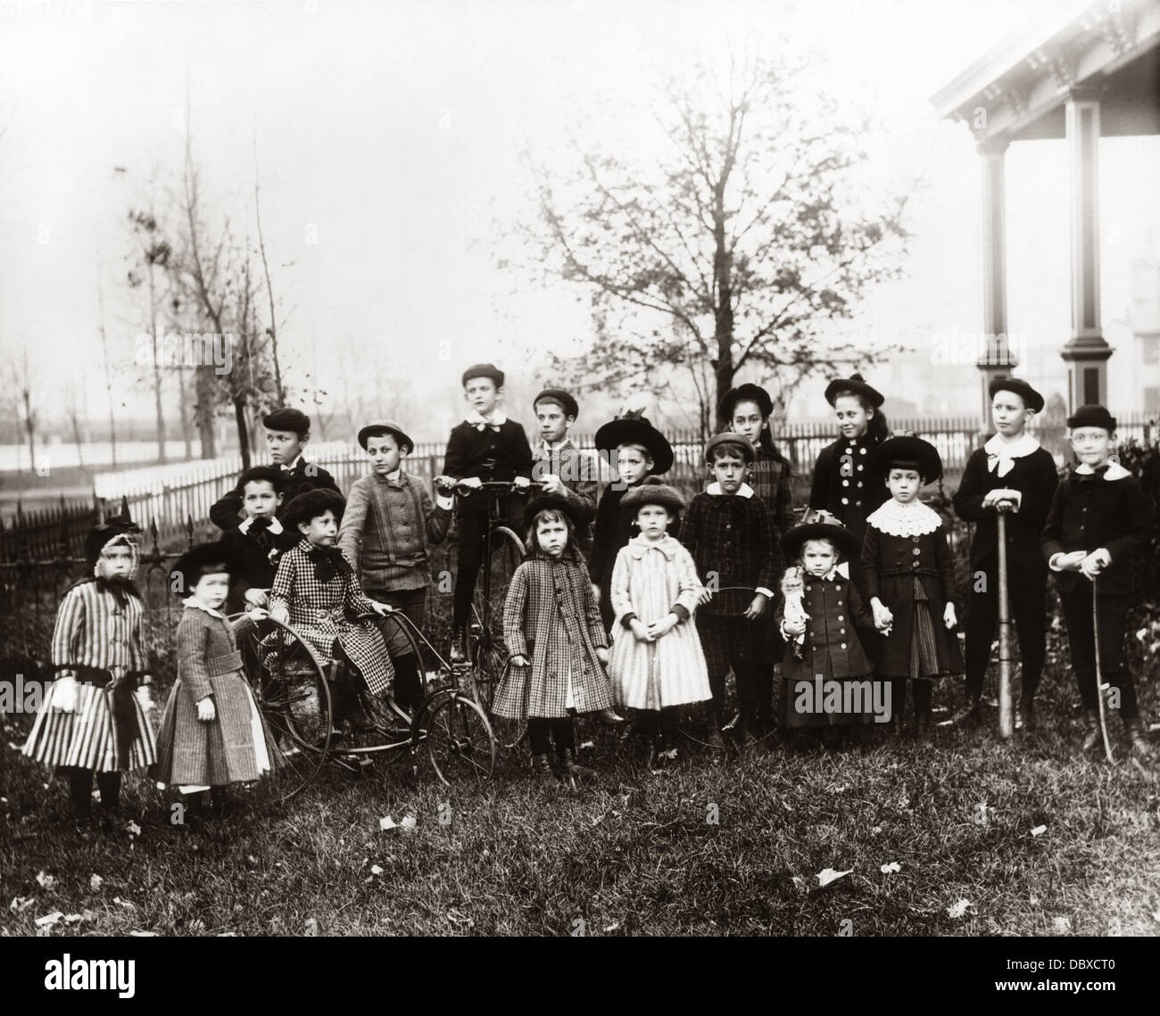 1890s 1900s POSED GROUP PORTRAIT OF 18 TURN OF THE 20TH CENTURY NEIGHBORHOOD CHILDREN ASSEMBLED IN SUBURBAN FRONT YARD Stock Photo