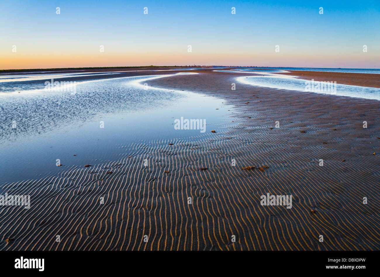 The wave pattern on the sand was softly lit as the sun sets in Bolivar Peninsula in Texas. Stock Photo