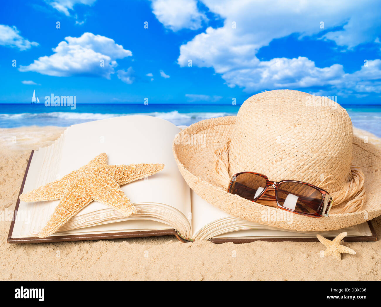 Straw hat with sunglasses and open book on sandy beach Stock Photo - Alamy