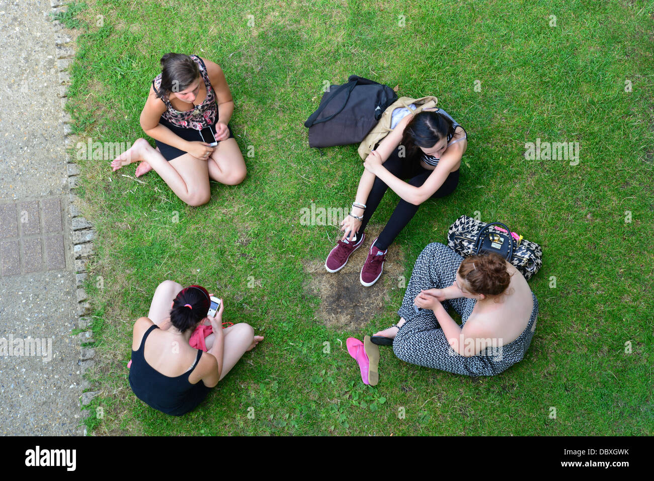 Group of young students sitting on riverbank at Goring Lock, Goring-on-Thames, Oxfordshire, England, United Kingdom Stock Photo