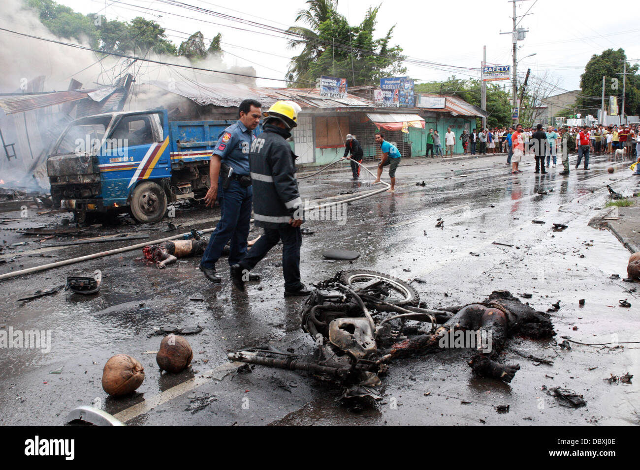 Cotabato, Philippines. 5th Aug, 2013. Bodies lay burnt in the street following a deadly car bomb explosion in the busy street of southern Philippine city of Cotabato. The deadly blast killed at least six people and wounded 29. It detonated as a car passed carrying a local official, who escaped unhurt. It was not clear if she was the target. Cotabato is on the island of Mindanao, which has been racked by a 40-year conflict between government forces and Islamist rebels. It is the second deadly bombing on Mindanao in 10 days. Stock Photo