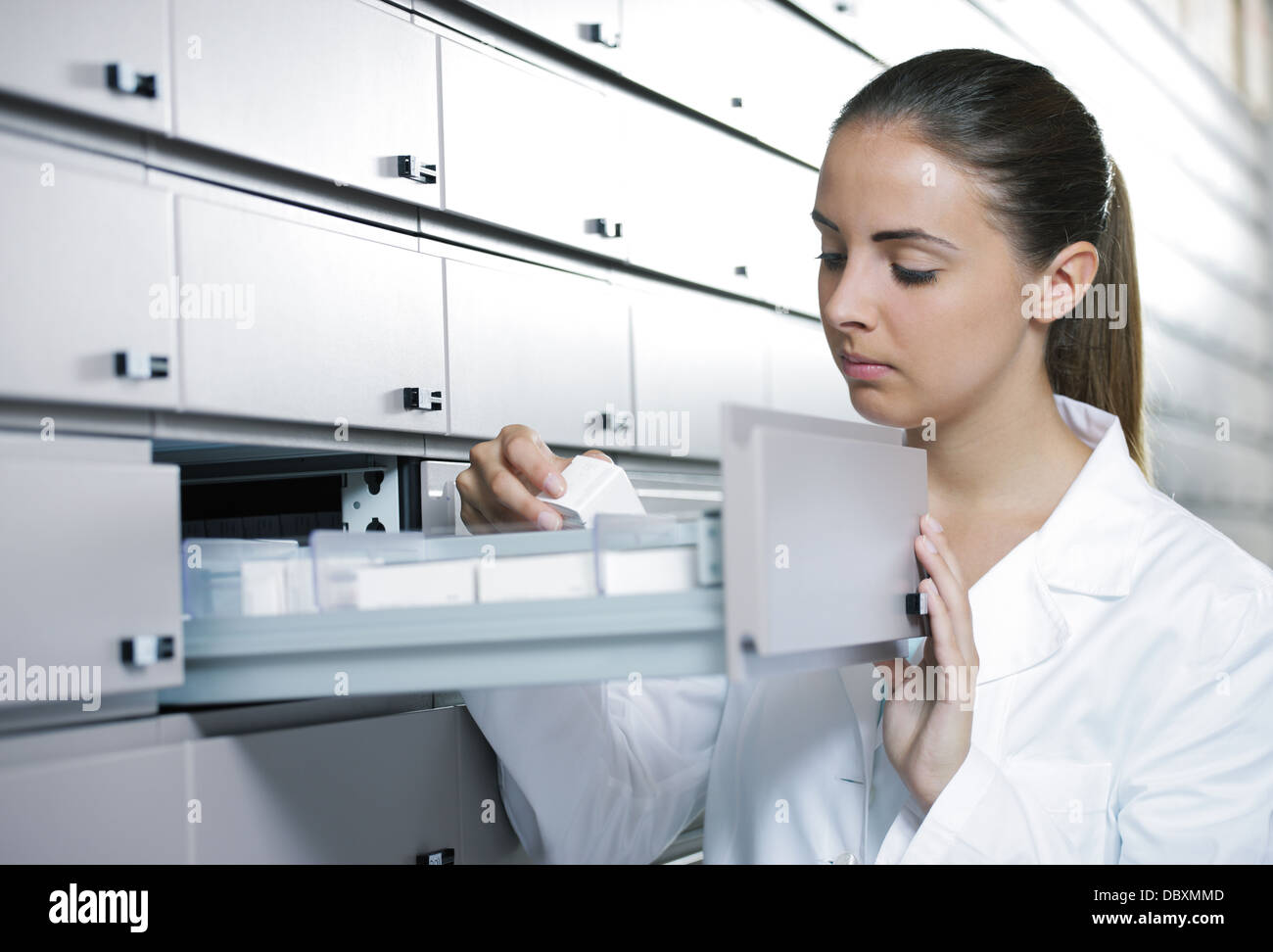 Young female pharmacist reaching for medicine Stock Photo