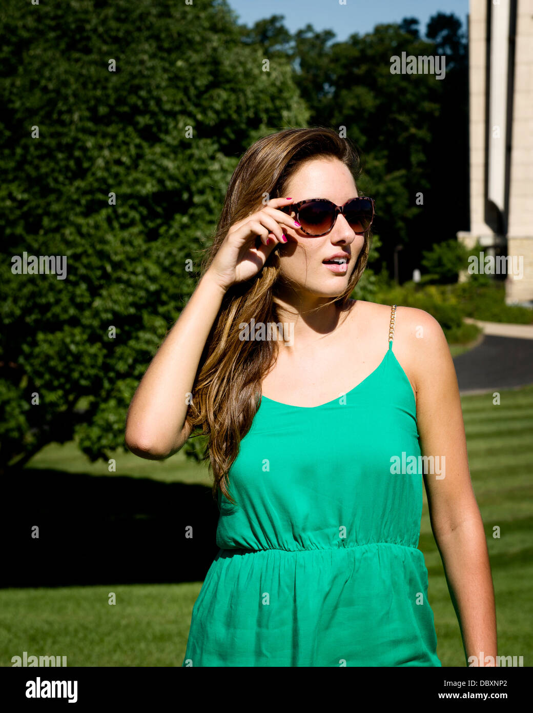 Woman in sunglasses and green dress outside on a sunny day. Stock Photo