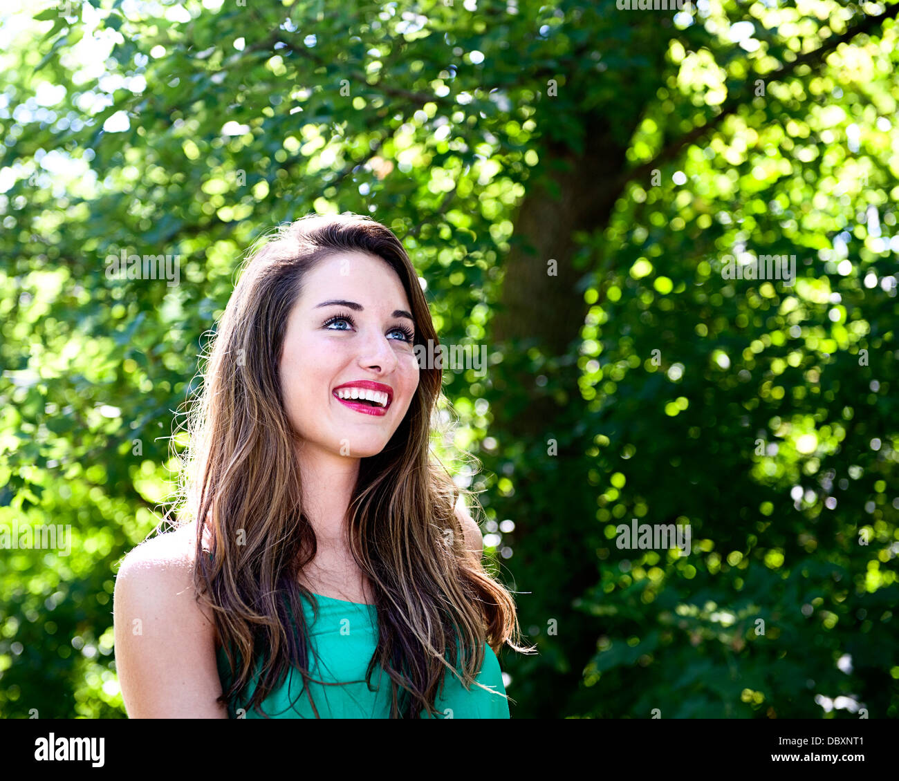 Portrait of attractive brunette woman with green leaves in the background. Stock Photo