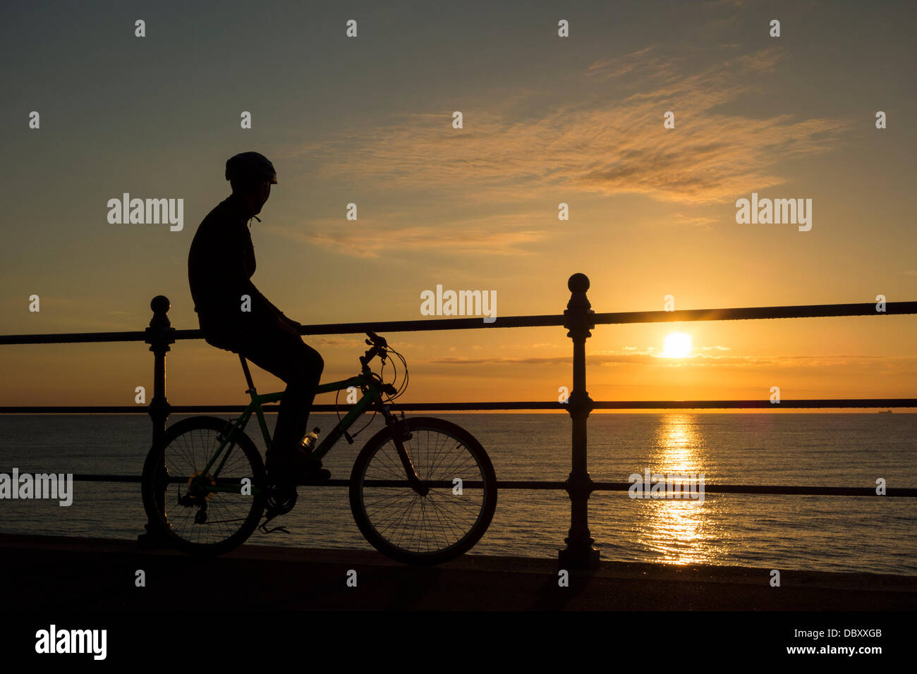 Mountain Biker watching sunrise at Seaton Carew near Hartlepool on the north east coast of England, UK Stock Photo