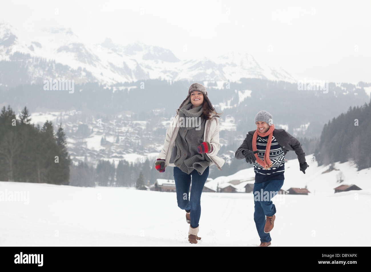 Happy couple running in snowy field Stock Photo - Alamy