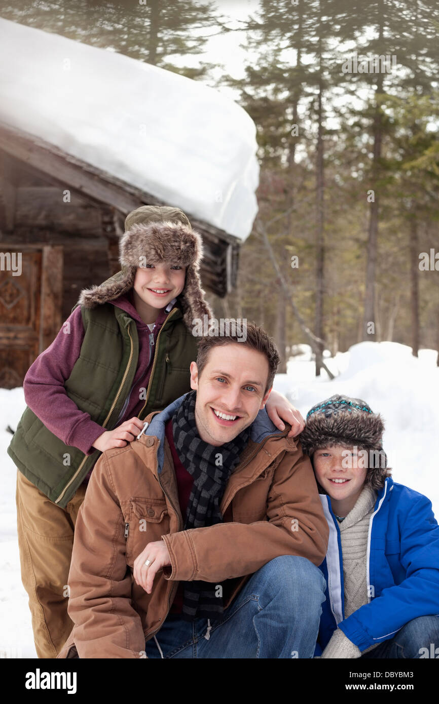 Portrait of smiling father and sons in snow outside cabin Stock Photo