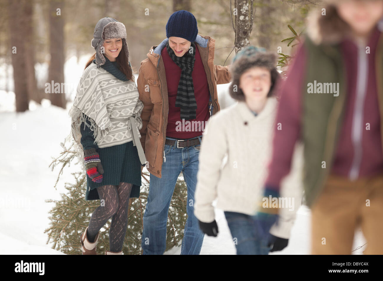 Happy family dragging fresh Christmas tree in snowy woods Stock Photo