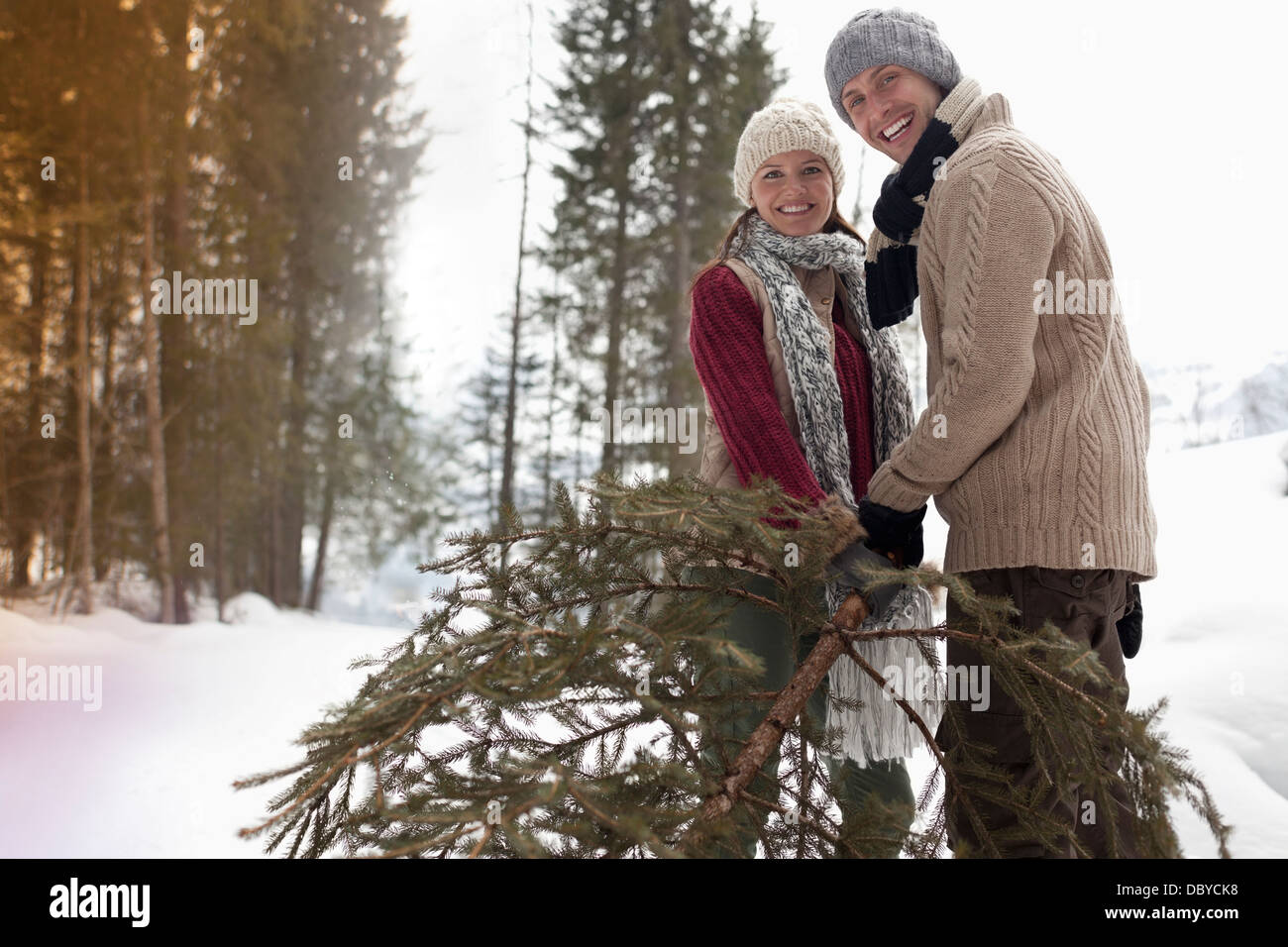 Portrait of happy couple with fresh Christmas tree in snowy woods Stock Photo