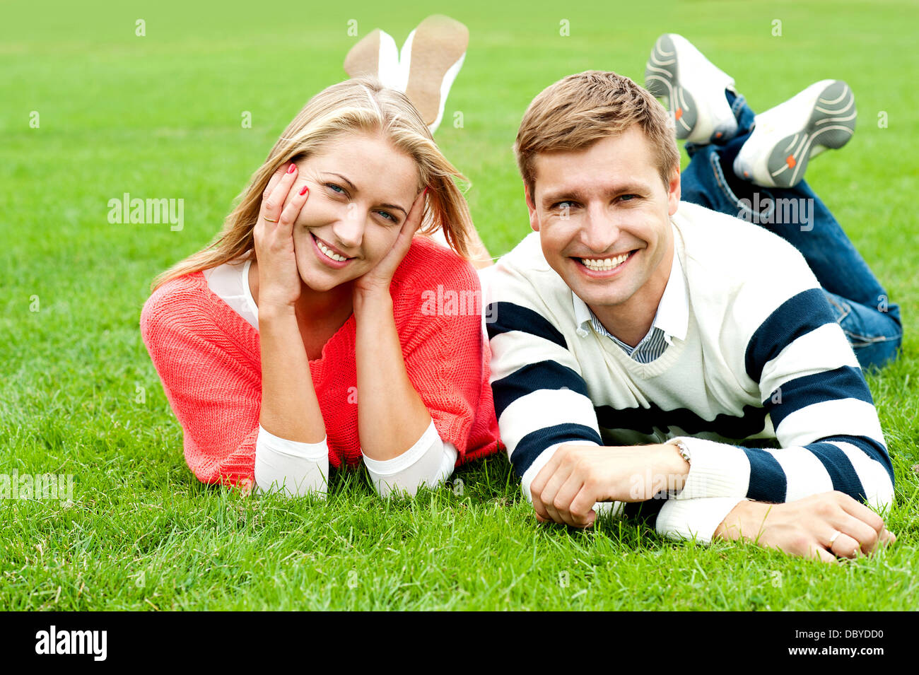 Charming young couple lying on green grass Stock Photo - Alamy