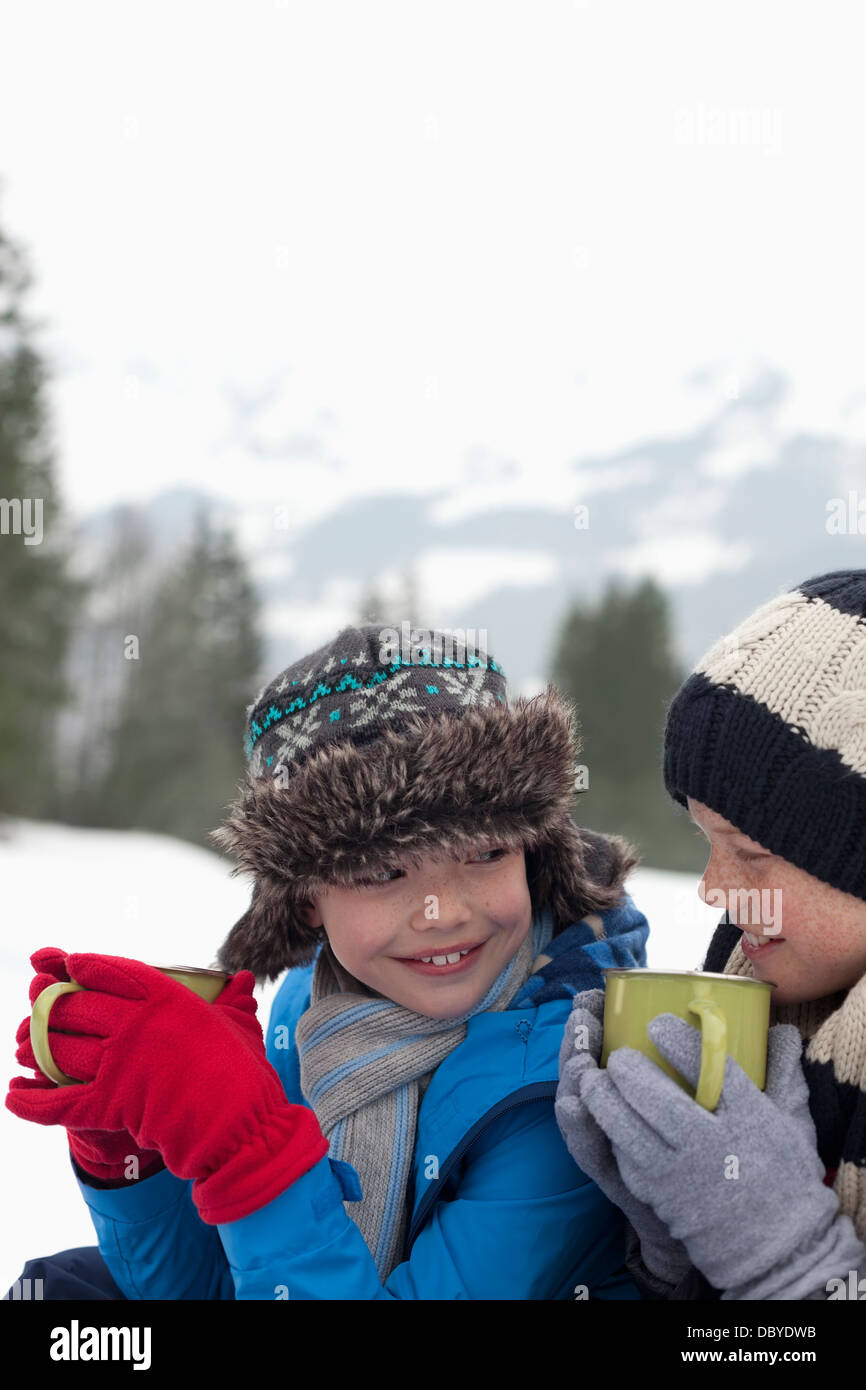 Close up of happy boys drinking hot chocolate in snowy field Stock Photo