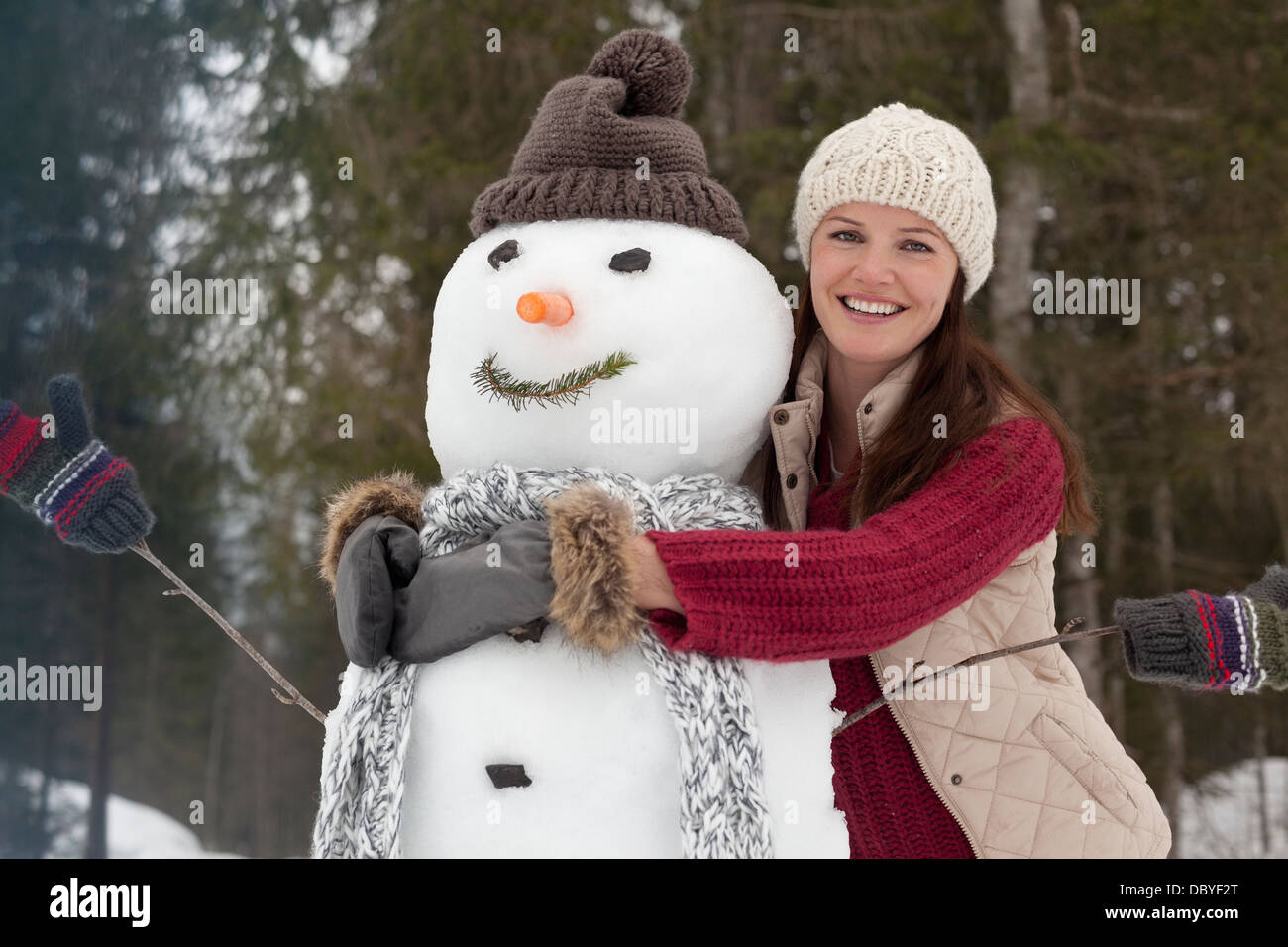 Portrait of smiling woman hugging snowman Stock Photo