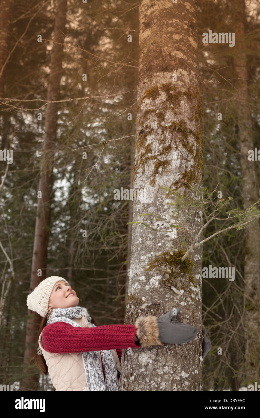 Smiling woman hugging tree trunk in woods Stock Photo