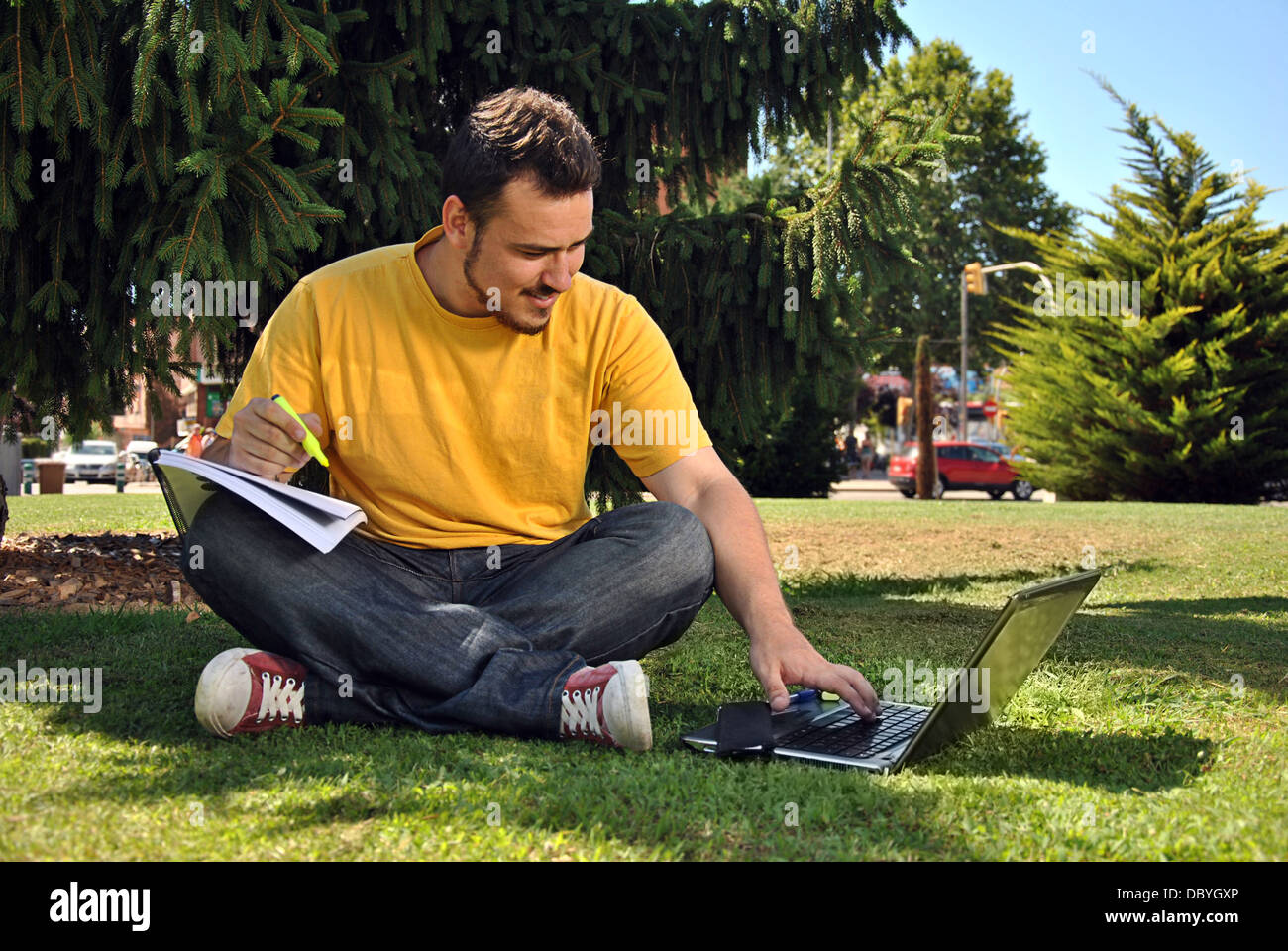 college student lying on the grass in the sun with a computer Stock Photo