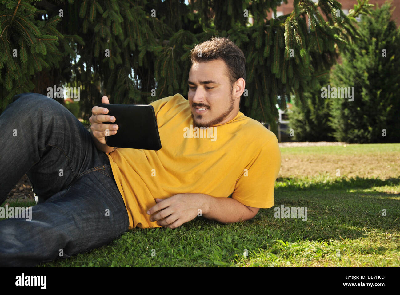 college student lying on the grass in the sun with a tablet Stock Photo