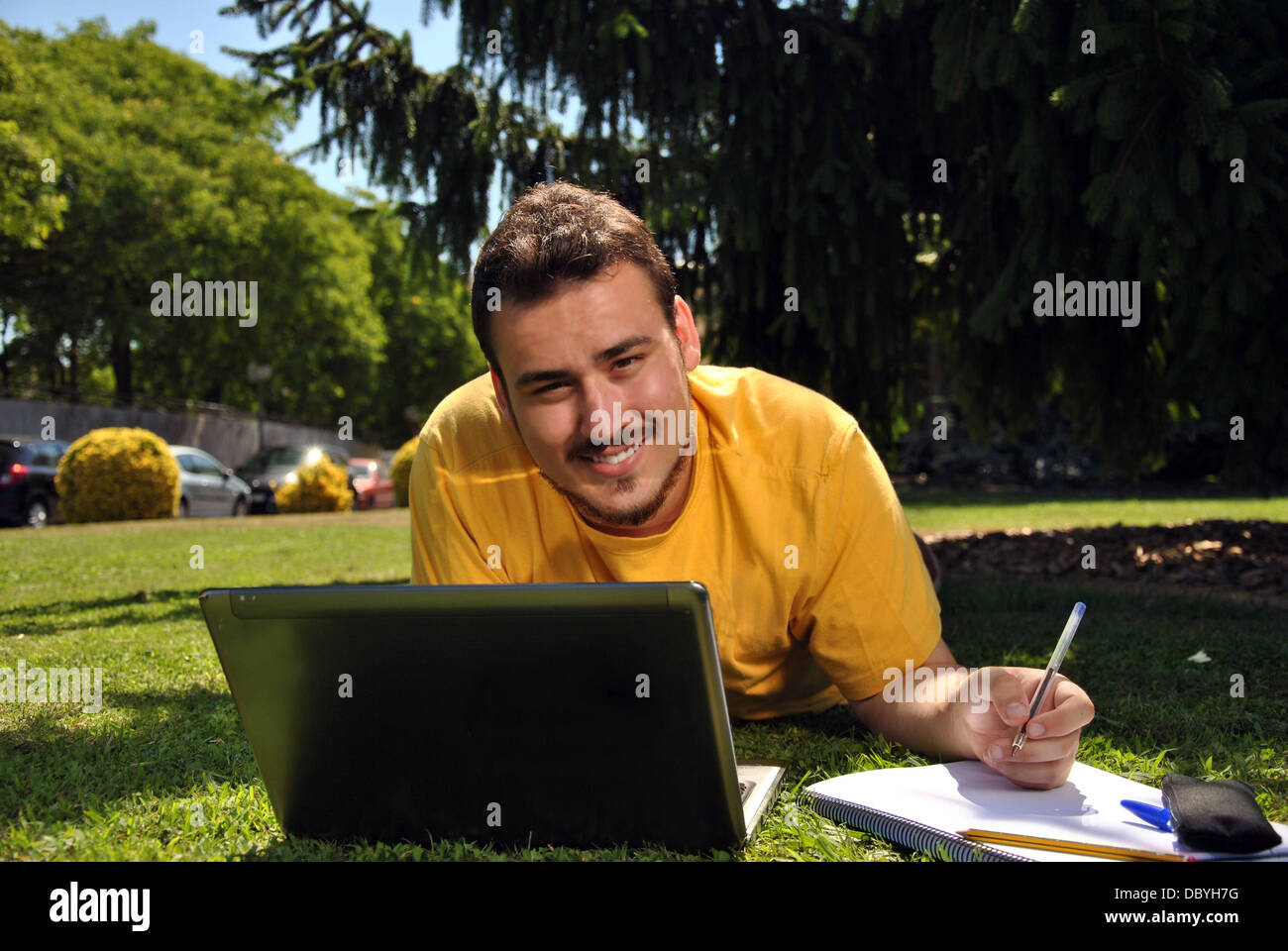 college student lying on the grass in the sun Stock Photo