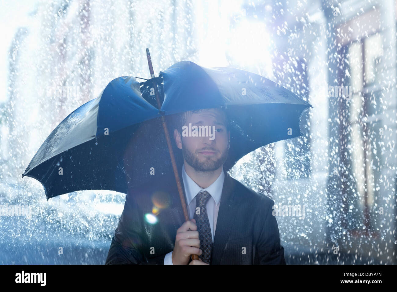 Frustrated businessman with broken umbrella in rain Stock Photo