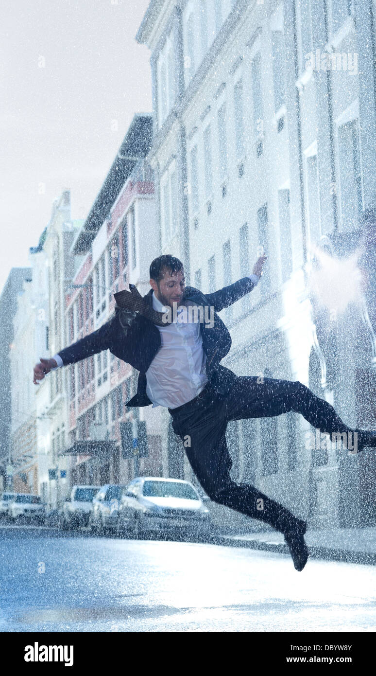 Businessman dancing in rainy street Stock Photo