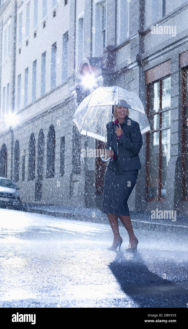 Businesswoman under umbrella in rainy street Stock Photo