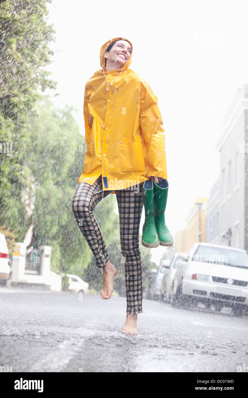 Happy woman dancing barefoot in rainy street Stock Photo