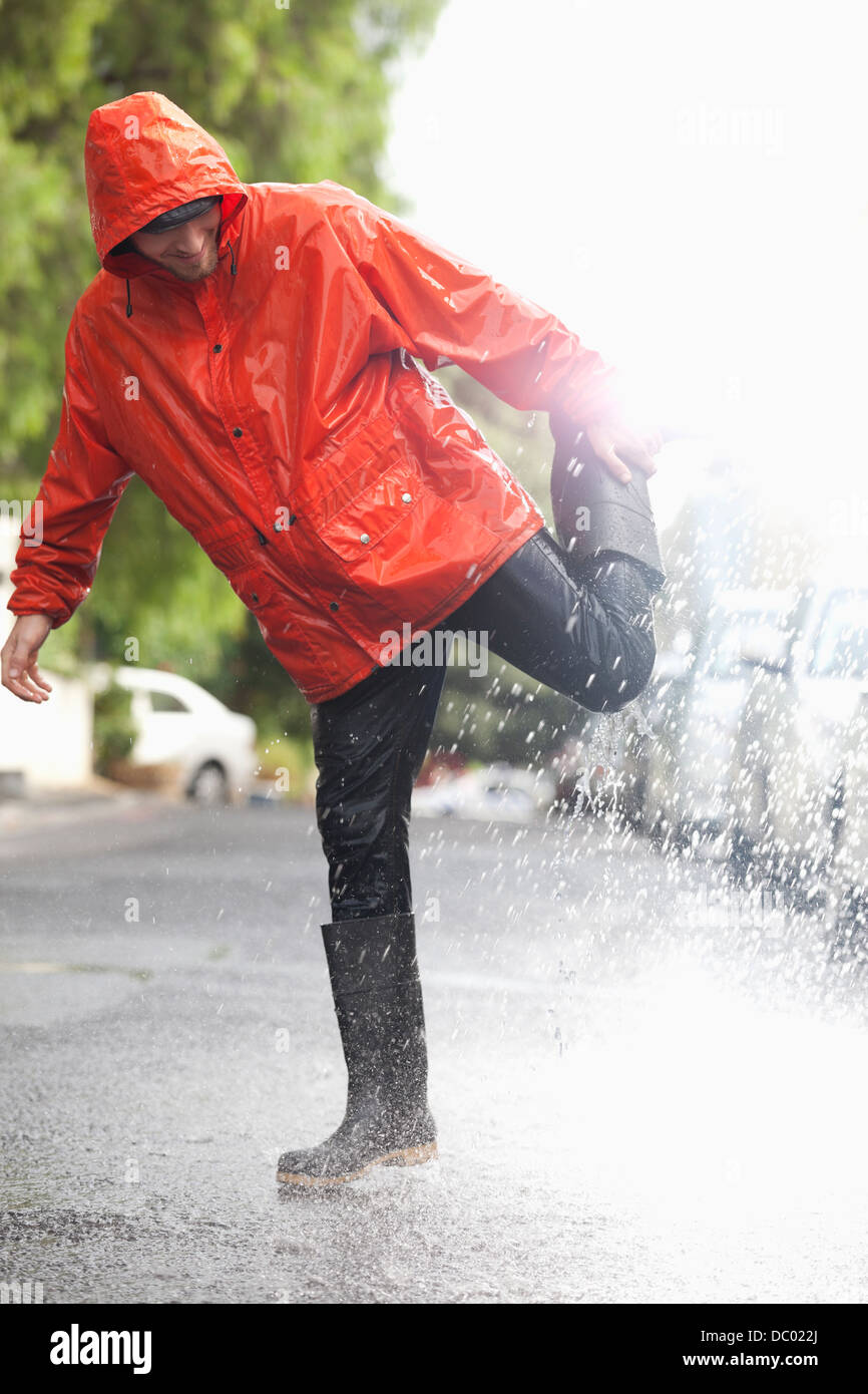 Man standing on one leg in rainy street Stock Photo