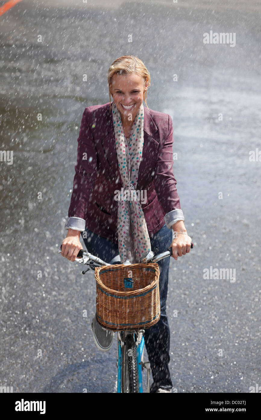 Happy woman riding bicycle in rainy street Stock Photo