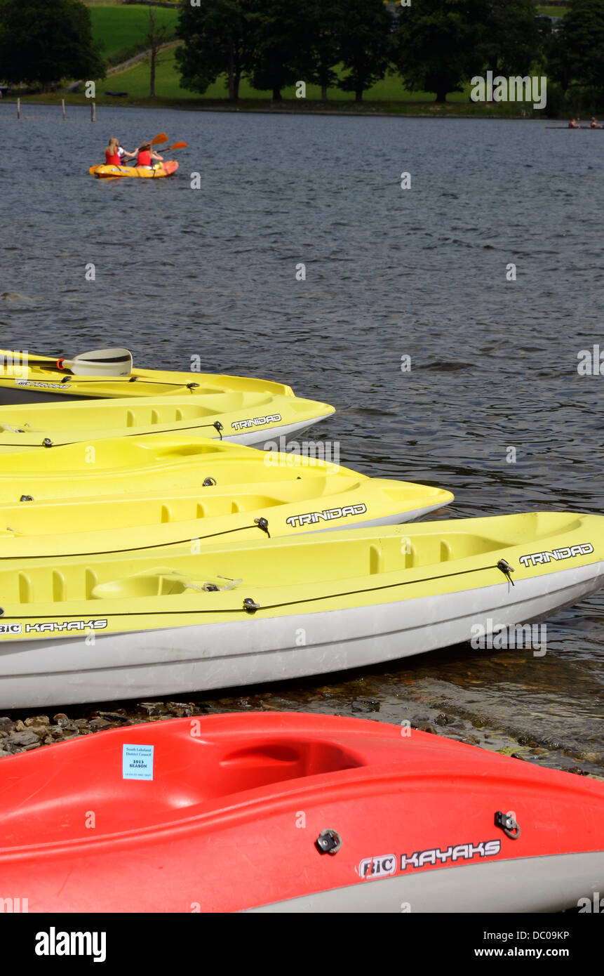 Colourful sit-on kayaks at Coniston Boat Hire at the edge of Coniston Water, Lake District National Park Stock Photo