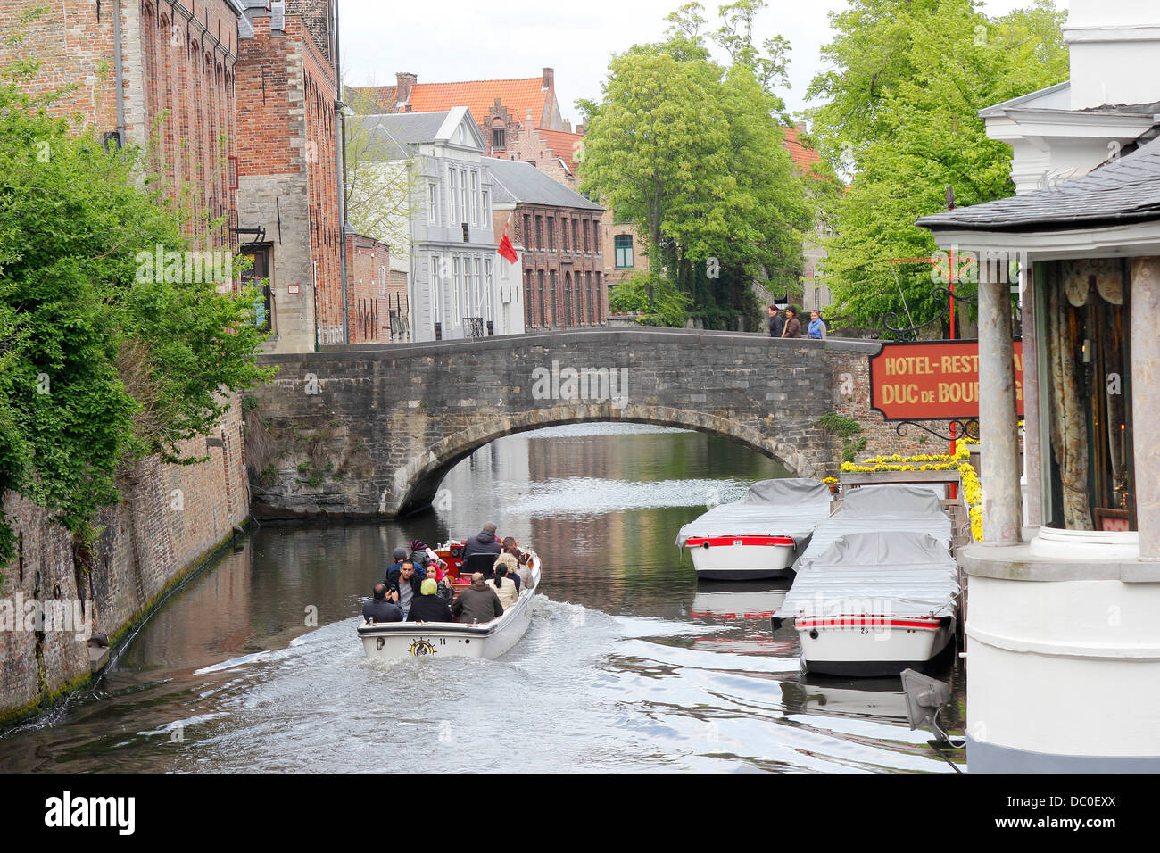 Bruges Belgium canal tour boat and stone bridges Stock Photo