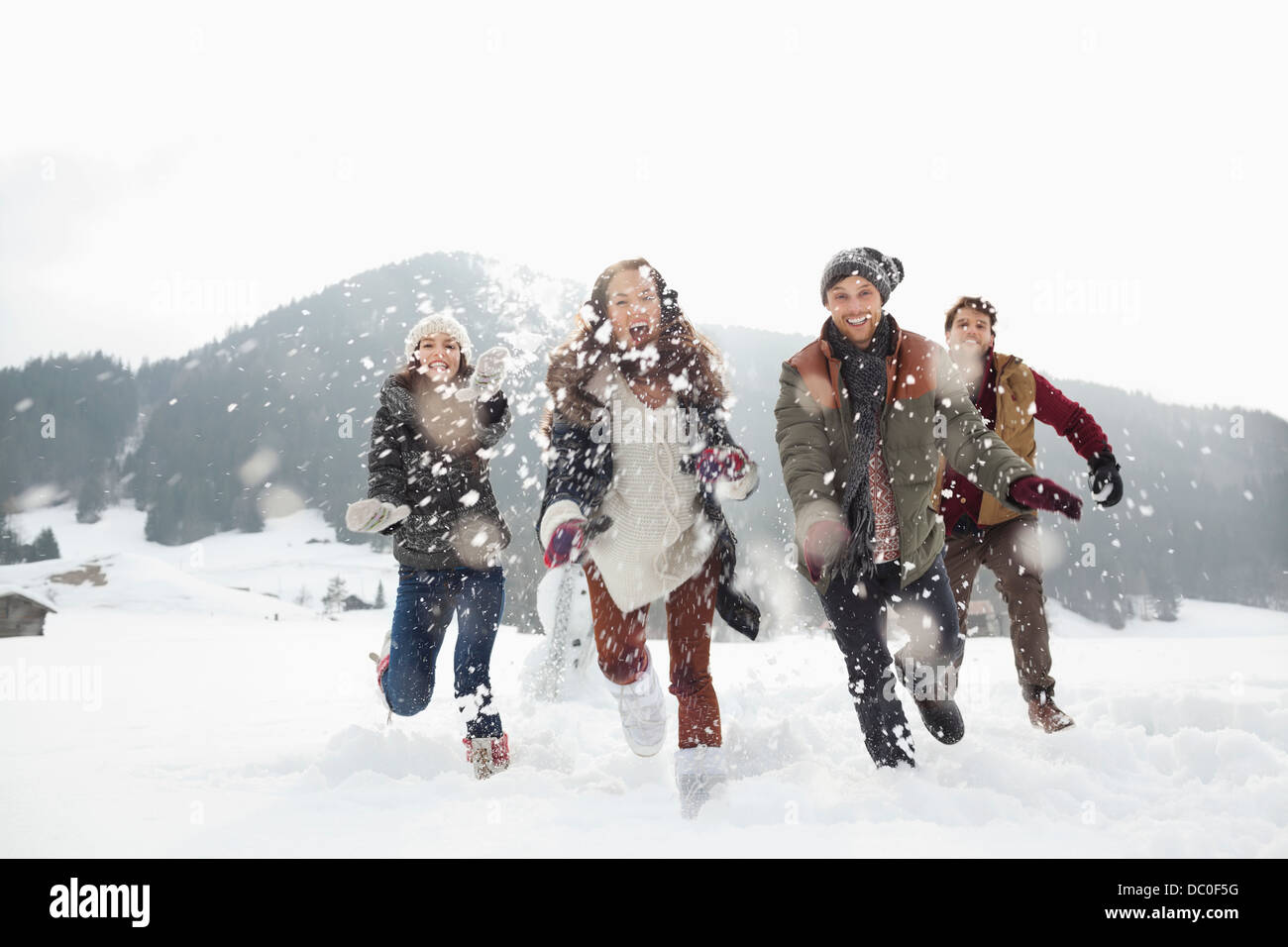 Happy friends playing in snowy field Stock Photo