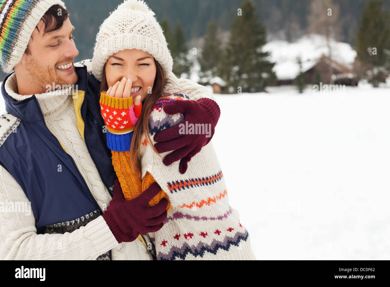 Couple laughing and hugging in snowy field Stock Photo