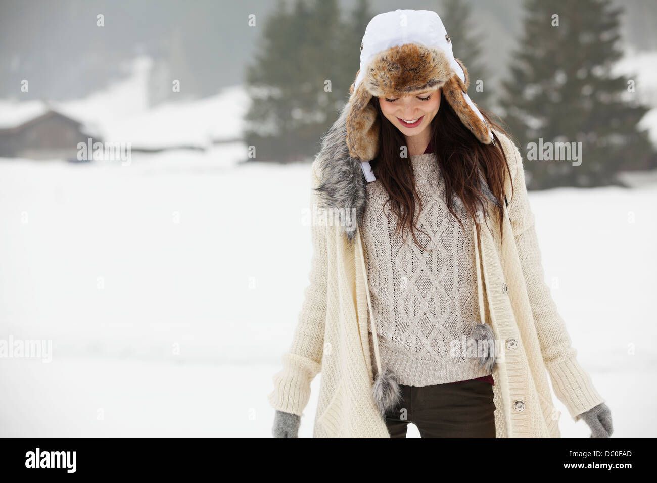 Smiling woman wearing fur hat in snowy field Stock Photo