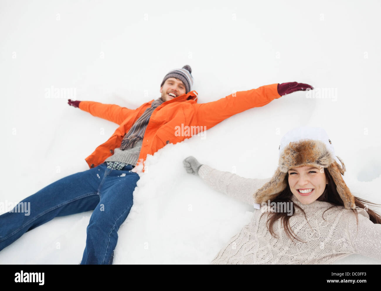 Portrait of happy couple making snow angels Stock Photo