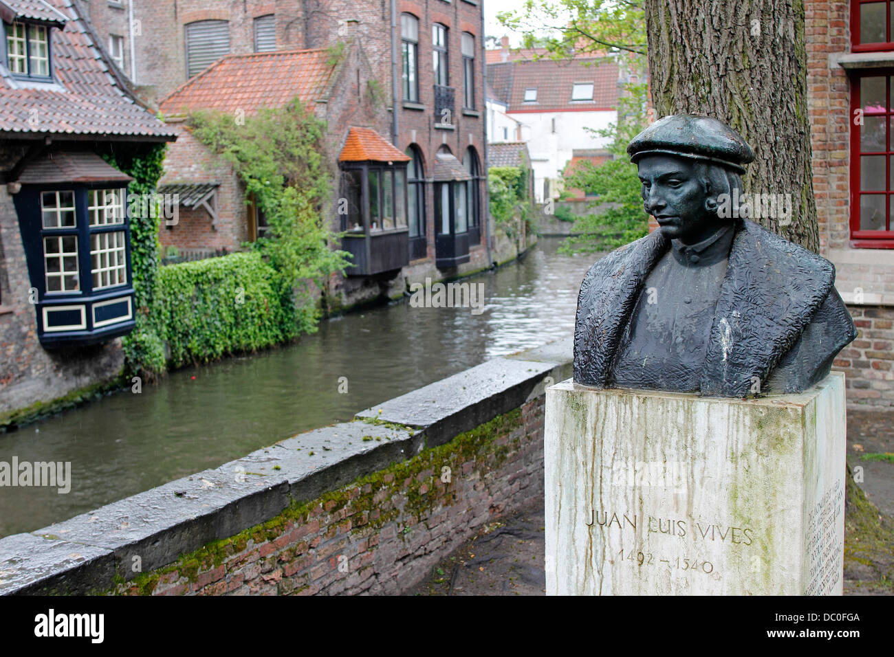 Bruges Belgium Flanders Europe Brugge statue Juan Luis Vives in park by canal in rain Stock Photo
