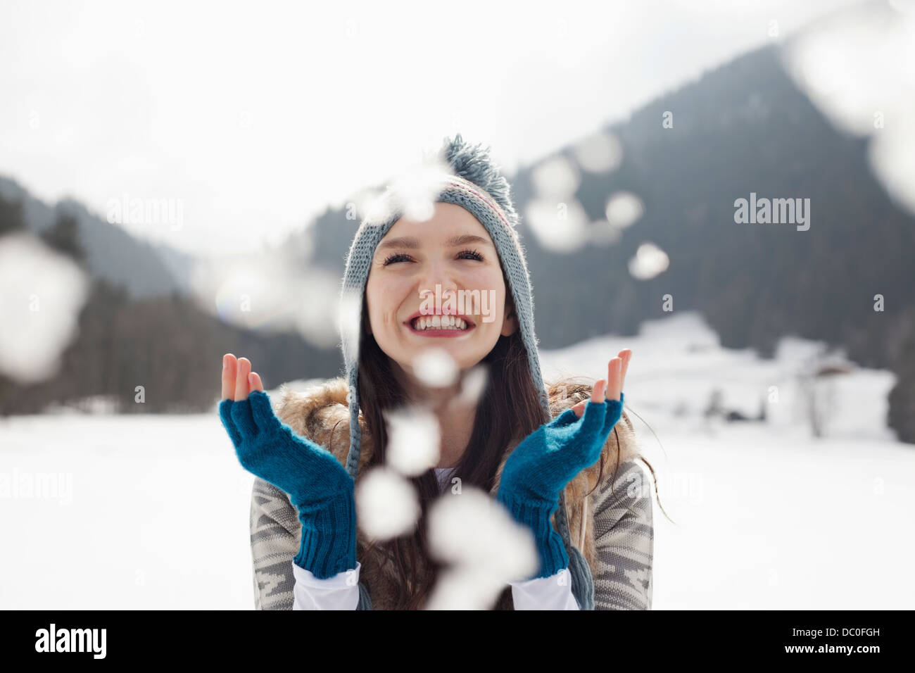 Happy woman enjoying falling snow in field Stock Photo