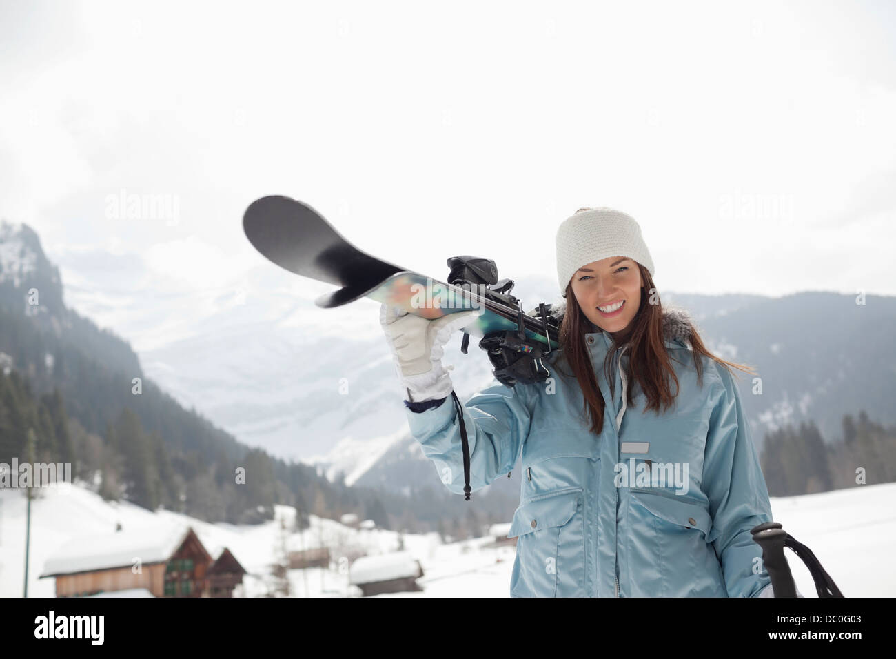 Portrait of enthusiastic woman carrying skis in snowy field Stock Photo