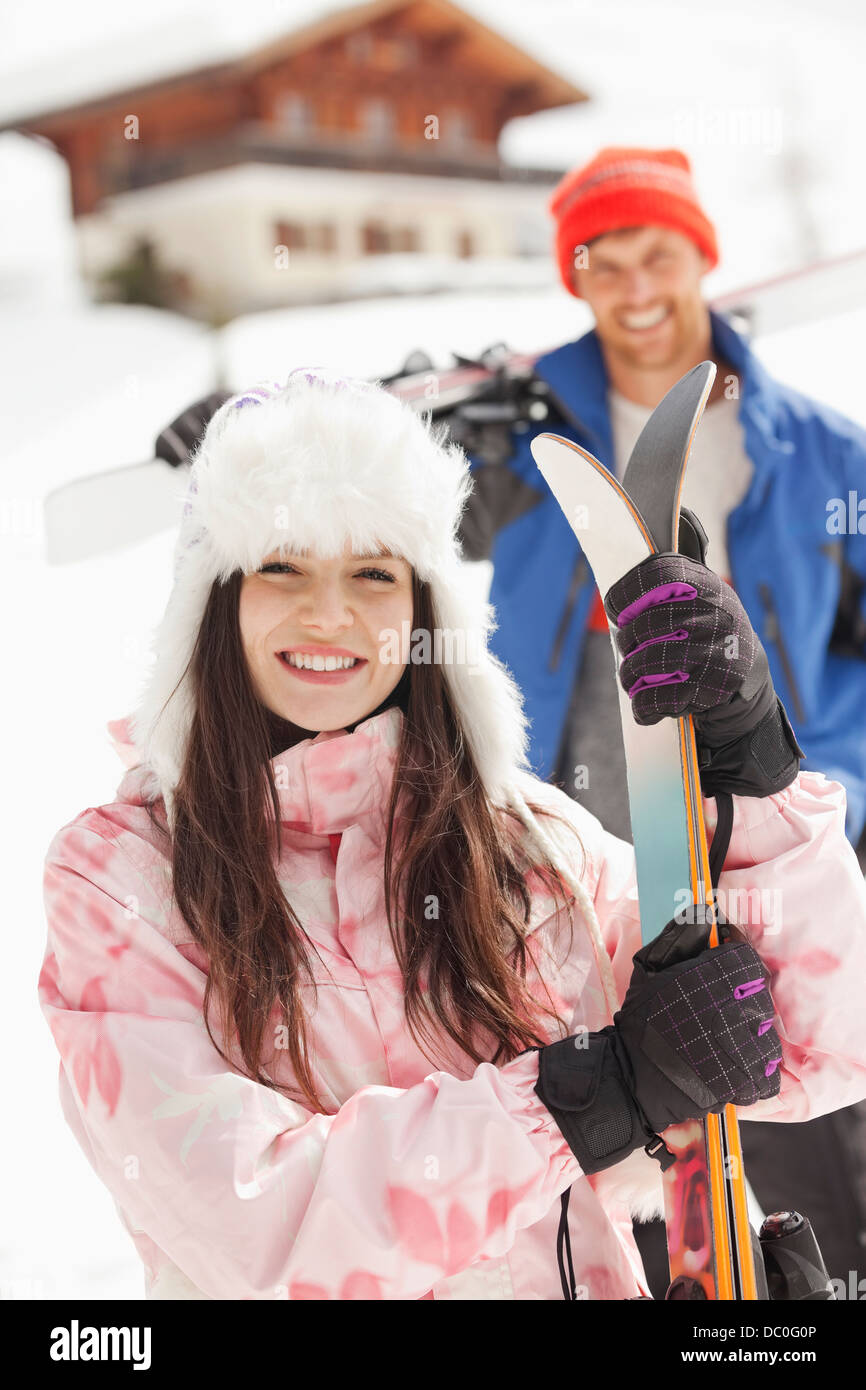 Portrait of smiling couple with skis outside cabin Stock Photo