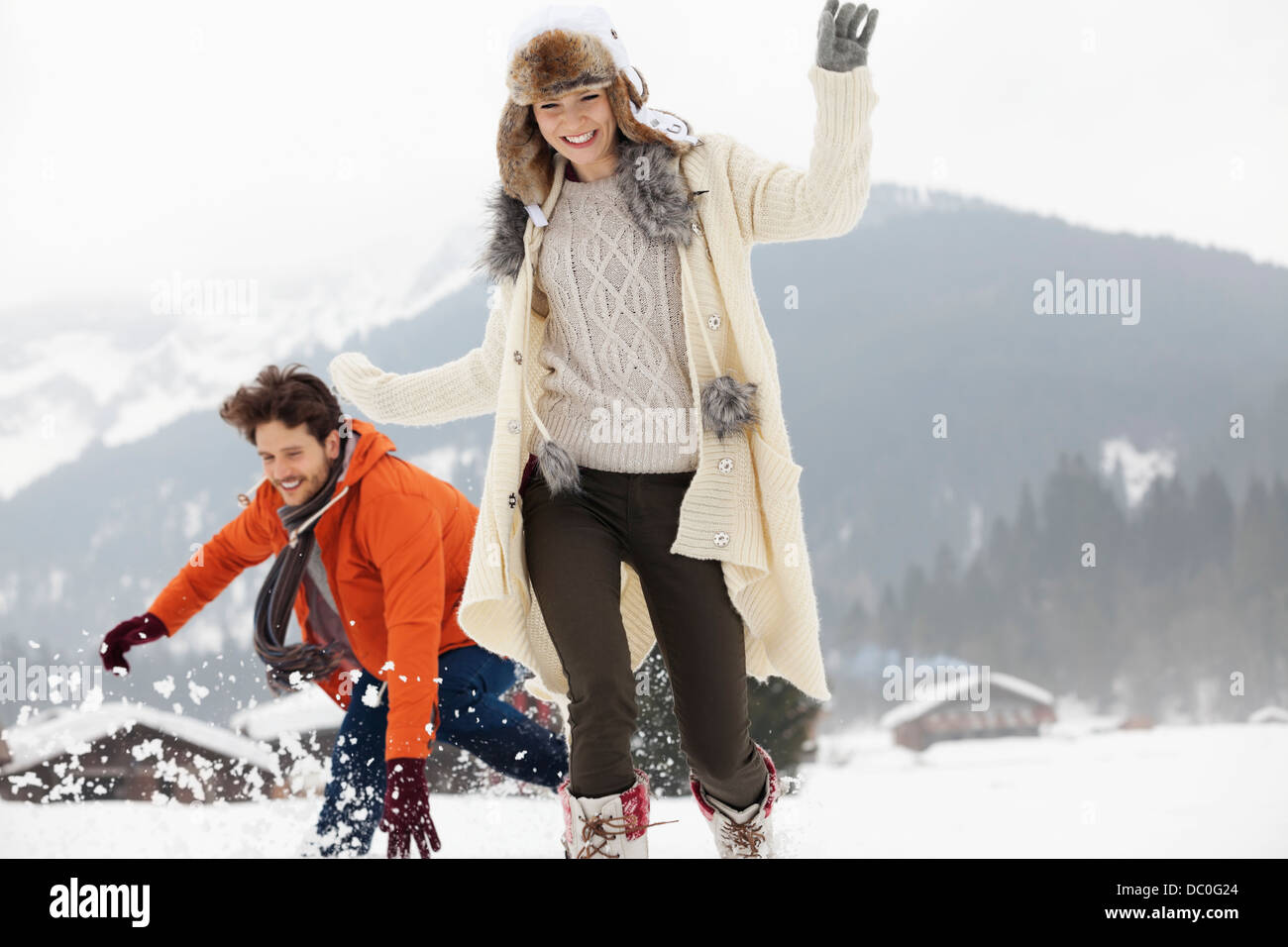 Playful couple running in snowy field Stock Photo