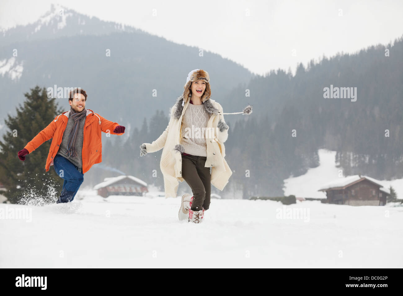 Happy couple running in snowy field Stock Photo - Alamy