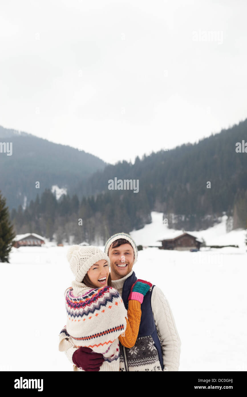 Portrait of happy couple hugging in snowy field Stock Photo