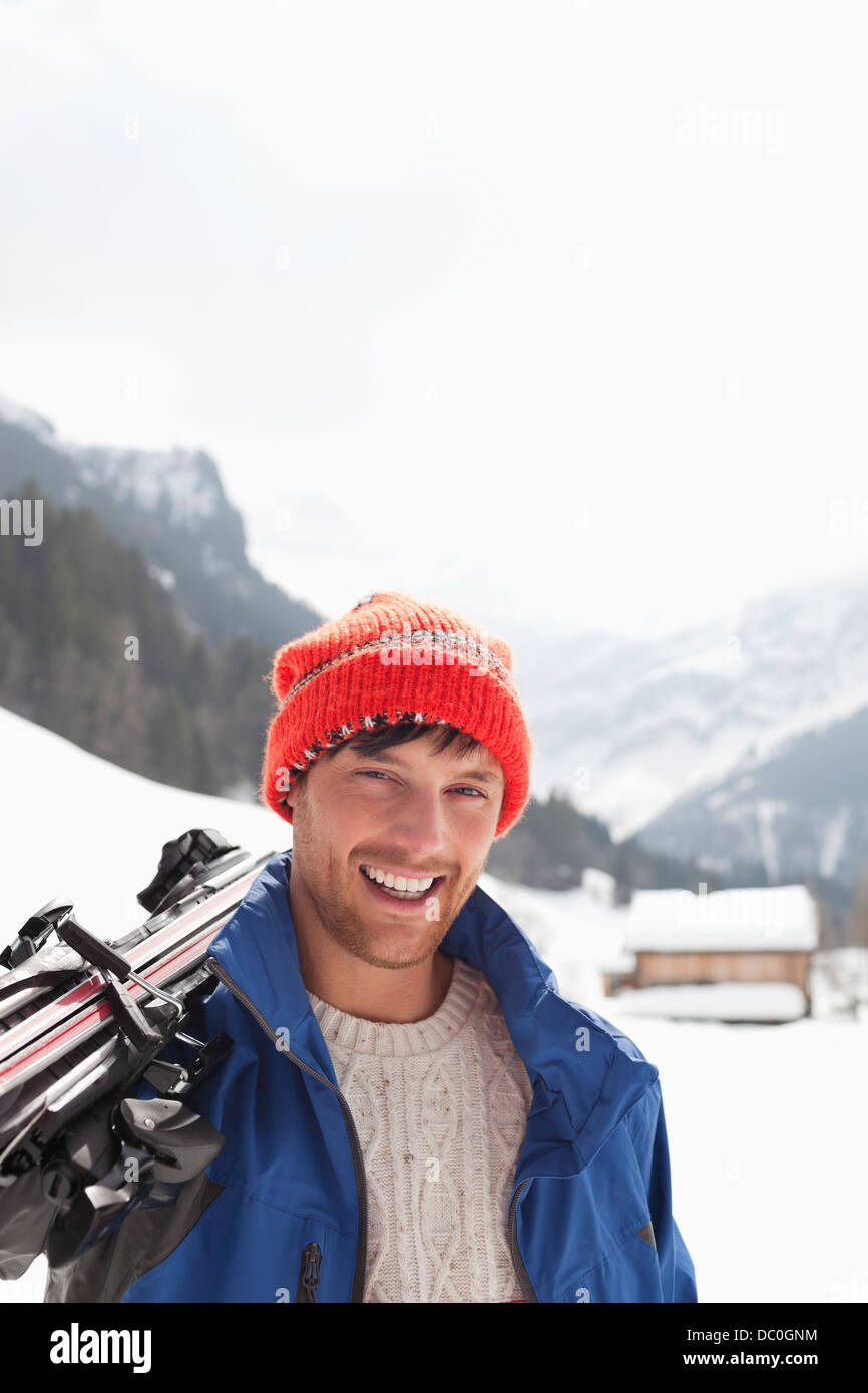 Close up portrait of smiling man carrying skis in snowy field Stock Photo