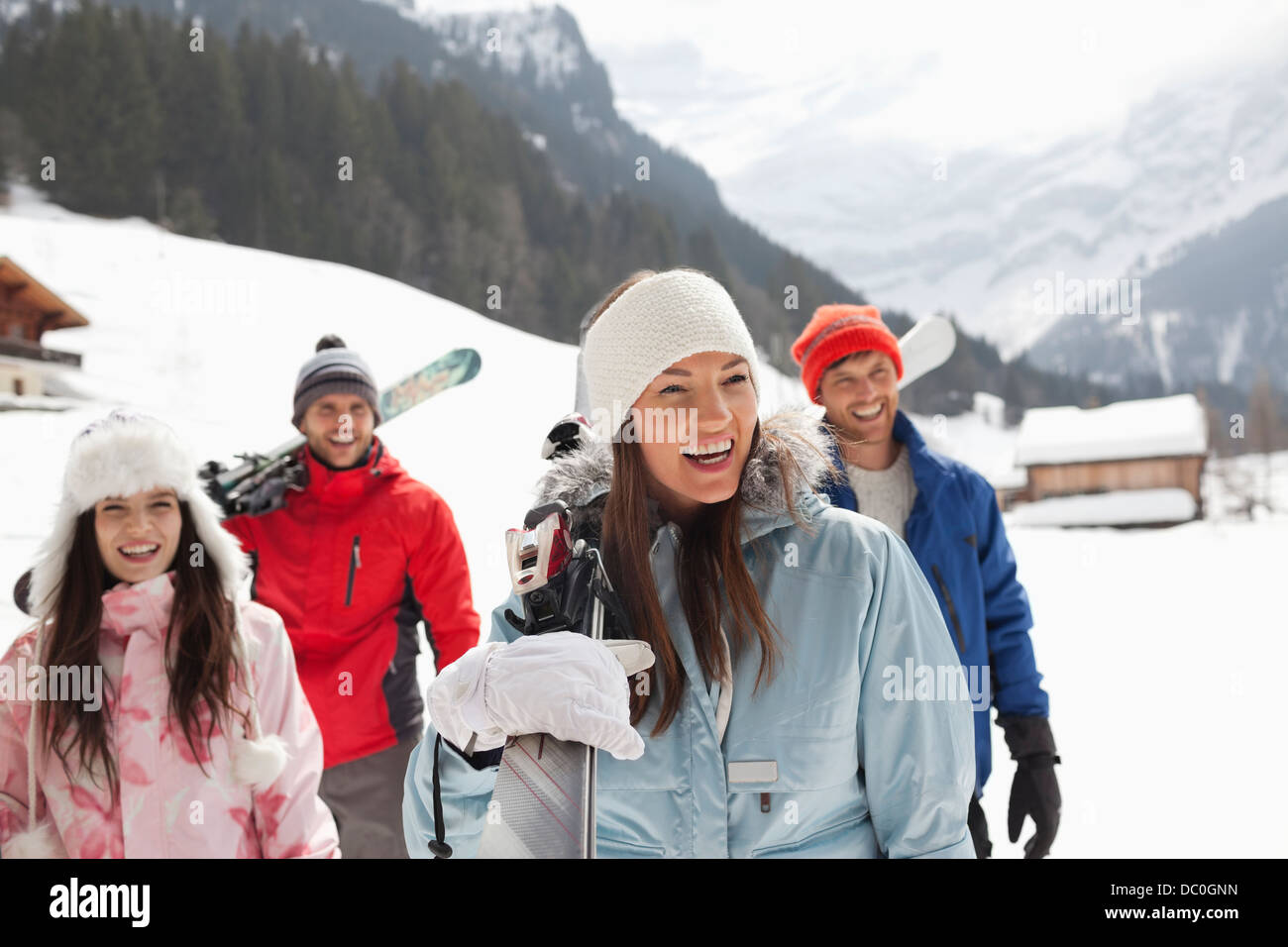 Happy friends carrying skis in snowy field Stock Photo