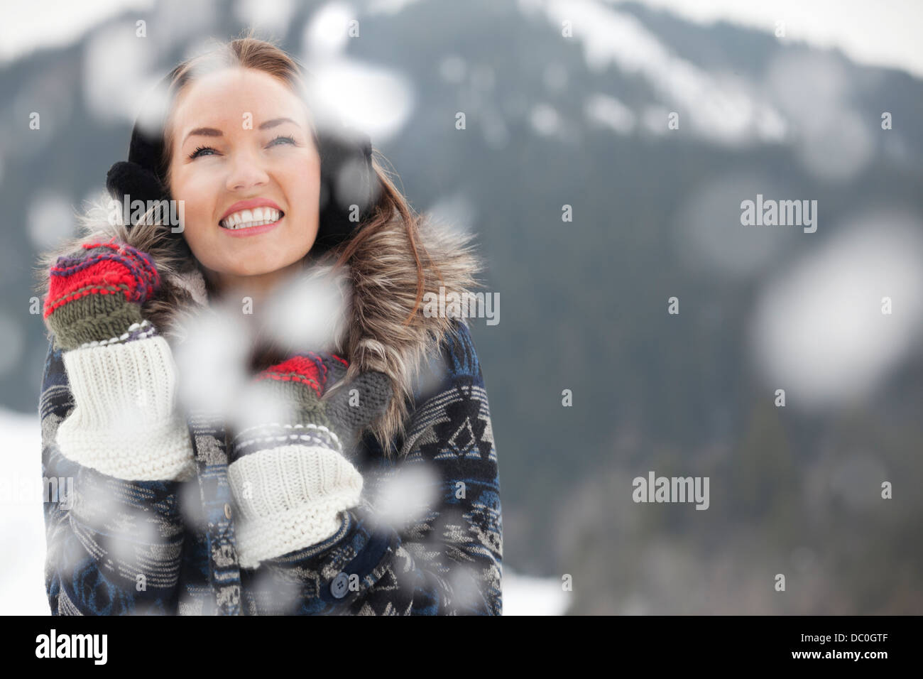 Happy woman wearing ear muffs and gloves in snow Stock Photo
