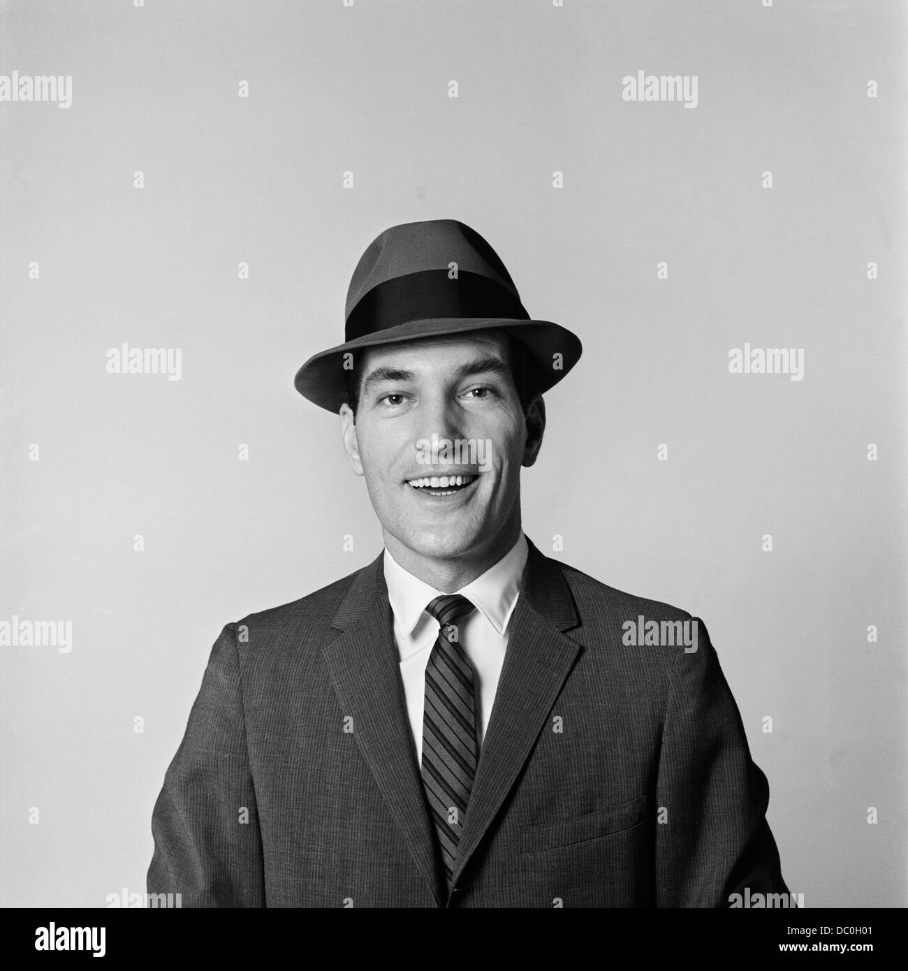 1960s PORTRAIT SMILING BUSINESSMAN WEARING HAT BUSINESS SUIT TIE LOOKING AT CAMERA Stock Photo